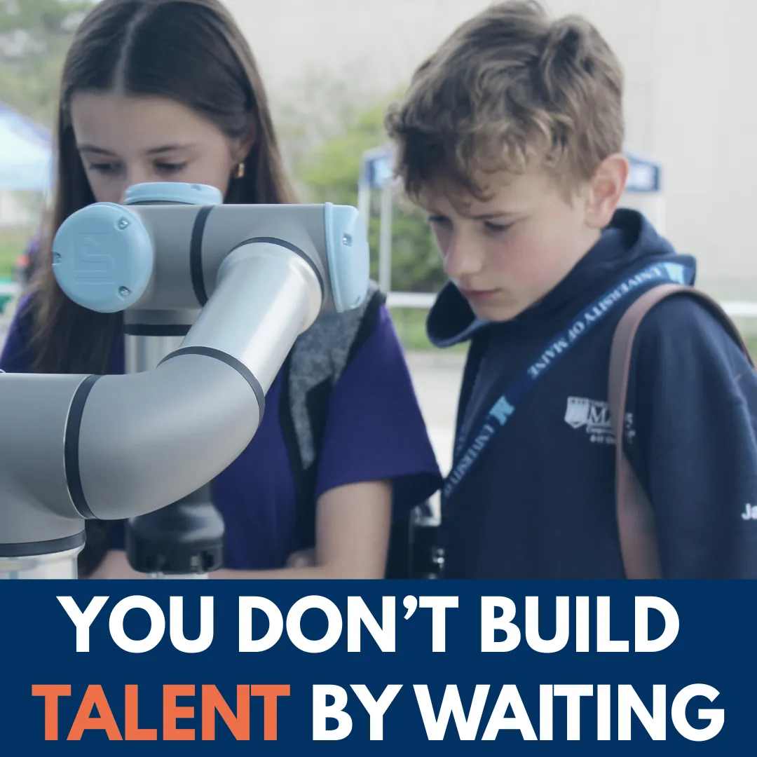 Students looking at a collaborative robot arm, with the line You don't build talent by waiting.